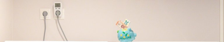 Twee stekkers in een stopcontact met een spaarpot met geld