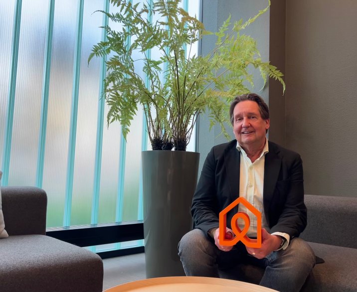 Wethouder Dolf Warris op de bank met een logo van een huis